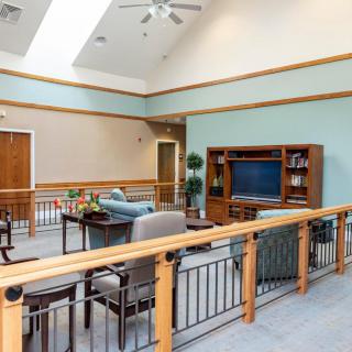 A modern living room with comfortable seating and a large television, featuring bright lighting and tasteful wooden accents.