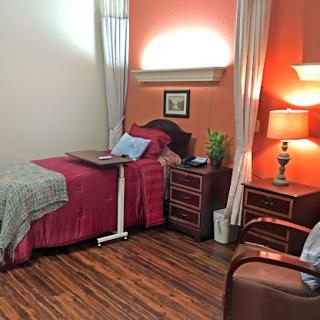 A cozy and warmly decorated bedroom featuring a neatly made bed, bedside lamp, and a touch of greenery.
