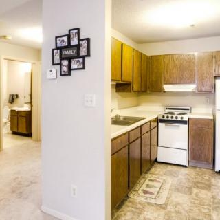 A compact kitchen with wooden cabinets and basic appliances in an apartment setting.
