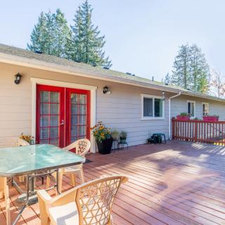 A spacious outdoor deck with a table, chairs, and red double doors leading into the house.