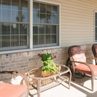 A cozy patio area with chairs and a table featuring a potted plant.