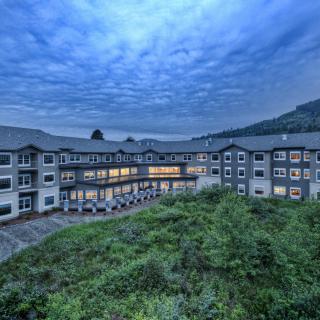 A scenic view of a modern hotel building surrounded by greenery under an evening sky.