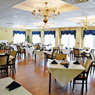 An elegantly arranged restaurant dining area featuring tables with white linens and a chandelier.