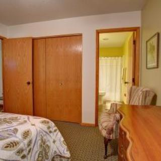 A cozy bedroom with a bed, wooden closet doors, a chair, and a small desk.