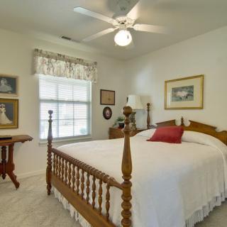 A cozy bedroom with a wooden bed, decorated with framed artwork and a ceiling fan.