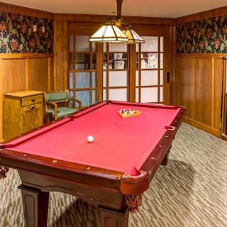 A cozy game room featuring a red-felt pool table under a decorative light fixture.