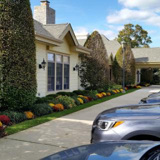 A serene view of a well-maintained building with landscaped gardens and parked cars.