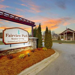 Entrance to Fairview Park Senior Living with a welcoming sign and scenic landscaping at sunset.