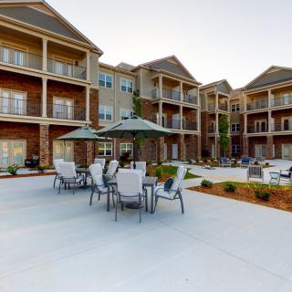 An outdoor seating area in front of a modern apartment complex with multiple balconies.