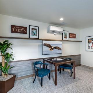 A stylish home office featuring a wooden desk, two blue chairs, and various artworks on the walls.