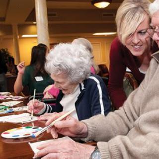 Seniors engaging in a group painting activity at a care center.