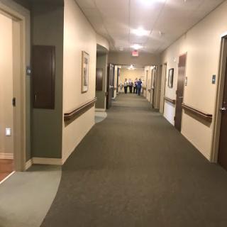 A spacious and well-lit hallway in a healthcare facility, featuring closed doors on either side.