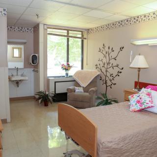 A well-lit hospital room with a single bed and comfortable furnishings.