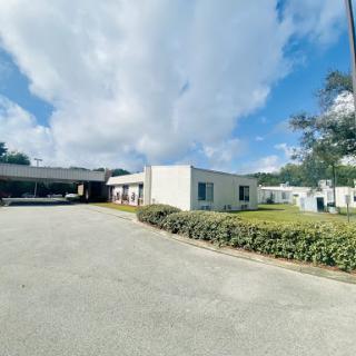 A view of a modern building surrounded by green grass and under a partly cloudy sky.