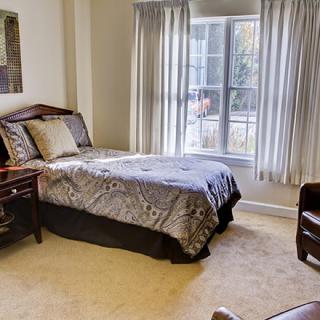 A cozy bedroom with a single bed and a large window.