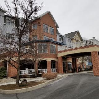 A charming residential building featuring a welcoming entrance and nearby trees on a cloudy day.