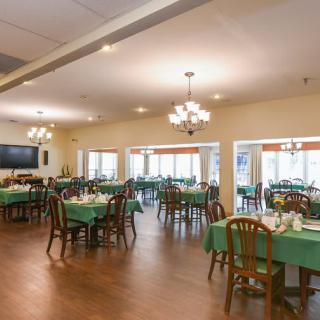 A spacious dining area with neatly arranged tables and chairs, illuminated by elegant chandeliers.