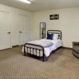 A minimalist bedroom featuring a single bed and carpeted flooring.