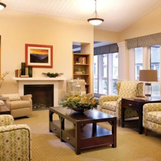 A cozy and well-furnished living room featuring a fireplace, sofas, and large windows.