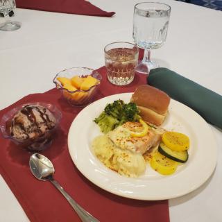A table set with a meal consisting of various dishes, a dessert, and drinks.
