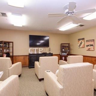 A cozy living room with comfortable chairs facing a television, complemented by decorative elements and a ceiling fan.