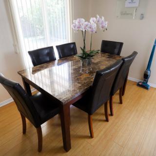 A dining area featuring a marble-top table with six leather chairs and a flower centerpiece.