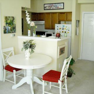 A bright and cozy dining area featuring a round white table with red cushions and elegant floral decor.