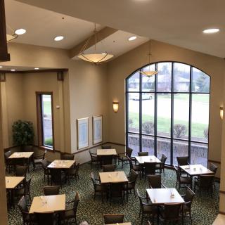 A spacious dining area with several tables and chairs, featuring large windows that allow natural light to fill the room.