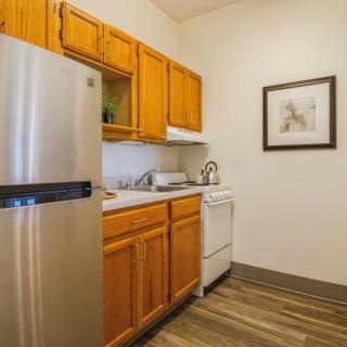 A compact kitchen with wooden cabinets and a stainless steel refrigerator.