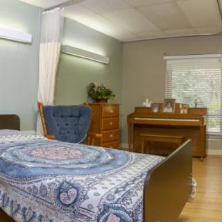 A cozy bedroom featuring a bed with a patterned blanket, a piano, and elegant furniture.