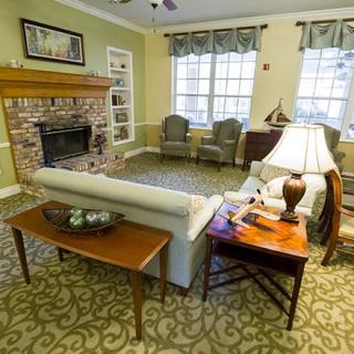 A cozy living room with a fireplace, sofa, and chairs arranged in a welcoming setting.