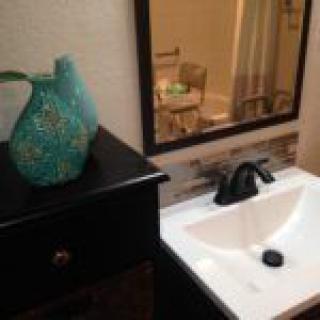 A bathroom sink area featuring a decorative vase next to a mirror.