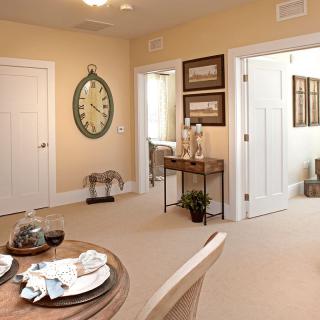 A cozy dining area featuring a clock on the wall, a neatly set table, and an adjoining hallway.
