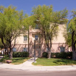 A residential building surrounded by green trees and a clear blue sky.