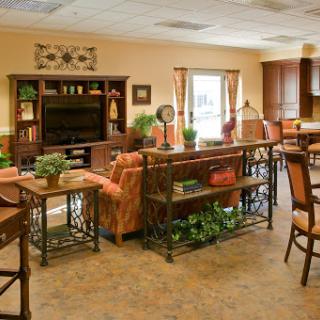 A cozy and well-decorated living room area with comfortable seating, plants, and a television.