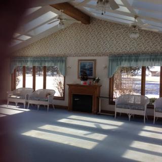 A bright and cozy interior space with large windows allowing sunlight to illuminate the room.