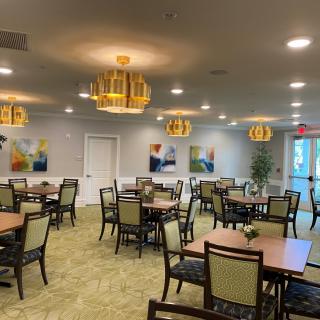 A spacious dining area with neatly arranged tables, chairs, and decorative lighting.
