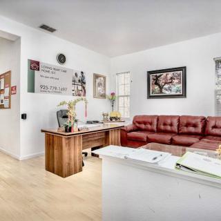 A modern office interior featuring a wooden desk, a red leather sofa, and various artworks on the walls.