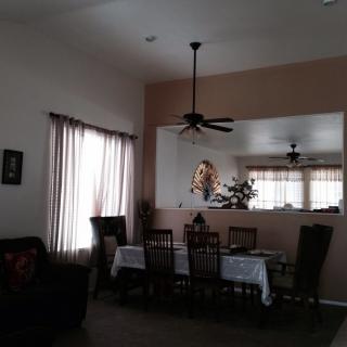 A cozy dining area with a table set for six, featuring a ceiling fan and natural light from the window.