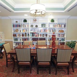 A cozy dining room with a large table surrounded by chairs, flanked by built-in bookshelves filled with books and decor.