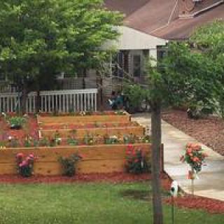A well-maintained garden with raised flower beds and a pathway leading to a house.