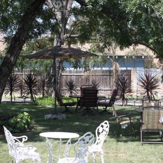 A peaceful garden setting with chairs and tables under the shade of trees.