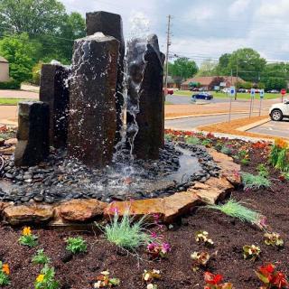 A serene waterfall feature surrounded by colorful flowers, enhancing the beauty of the landscape.