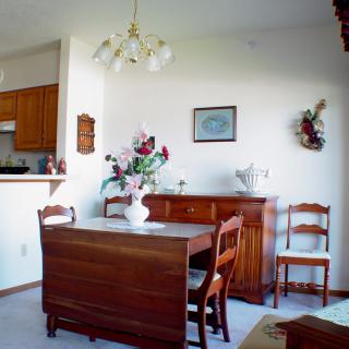 A cozy dining room with wooden furniture, including a table set for four and a decorative vase of flowers.