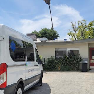 A parked ambulance outside a medical facility under a clear blue sky.