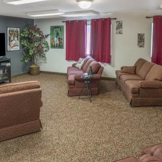 A cozy living room with brown sofas, a TV, and red curtains.