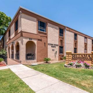 A charming residential building featuring landscaped grounds and a clear blue sky.