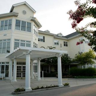 A view of a residential building with a covered entrance and landscaped surroundings.