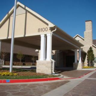 A building with a covered entrance, featuring columns and a driveway.