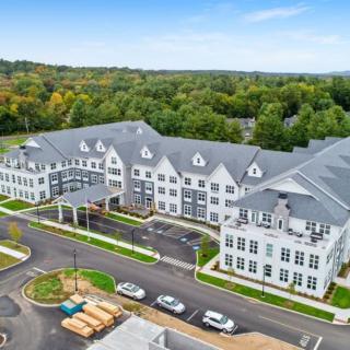 Aerial view of a large residential building surrounded by greenery and parking facilities.